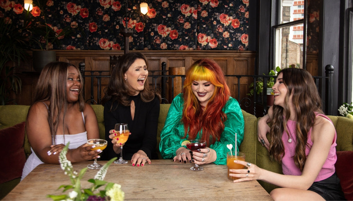 four women sat round a table laughing